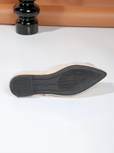Detailed view of the anti-slip black rubber sole on a beige pointed toe flat mule shoe