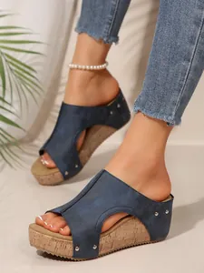 Détail rapproché de sandales compensées bleu marine avec rivets et semelle liège