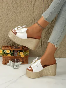 Elegante weiße Plateau-Pantoletten mit Schleife und Metallring am Fuß des Models