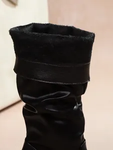 Detail view of black tall fashion boots with cozy faux fur lining and pleated shaft