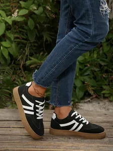 Retro zwart-witte GAT-sneakers met rubberen zool in een natuurlijke buitenomgeving.
