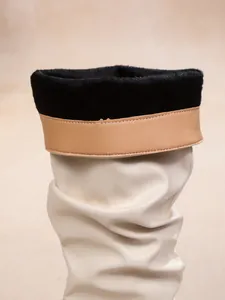 Close-up detail of cream leather slouchy boots with black faux fur lining and tan trim