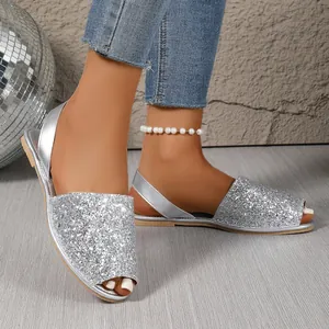 Close-up detail of sparkling silver sequins on stylish women's peep-toe flat sandals.