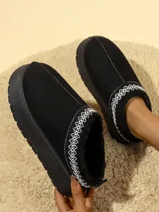Primer plano de zuecos con plataforma para mujer en negro con forro de pelo y bordados