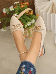 Close-up of beige suede flat sandals with golden horsebit buckle and pointed toe