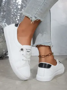 Close-up of women's white casual sneakers with black heel patch and metal eyelets.