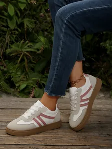 Detail van retro damessneakers met roze strepen op een houten pad in een natuurlijke setting