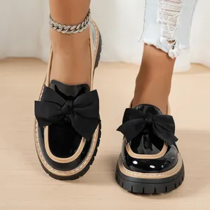 Detail shot of black patent leather loafers with oversized bow and chunky platform sole
