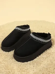 Primer plano de zapatillas tipo bota de nieve con plataforma negra y cuello bordado.