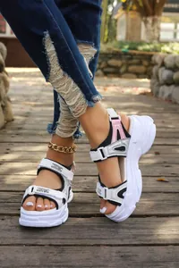 White chunky sports sandals with pink accents and thick platform soles on outdoor deck