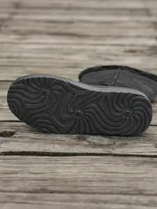 Detailed macro view showing anti-slip pattern on the sole of black winter snow boots