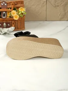 Unteransicht der Plateau-Pantolette mit rutschfester Wellenstruktur und schwarzer Schleife