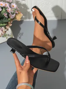 Close-up detail of stylish black thong sandals featuring a square toe and elegant kitten heel