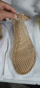 Close-up of sparkling rhinestone embellishments on a beige fishnet flat sandal