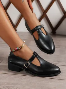 Elegant black T-strap Mary Jane loafers with low chunky heels shown on a model's feet.