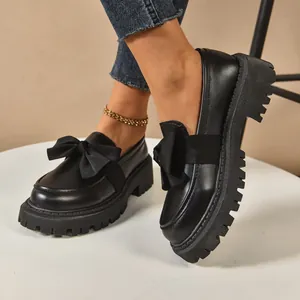 Stylish black platform loafers with a large bow, chunky lug sole for women.