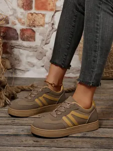 Close-up van retro sneakers voor dames in kaki en geel op een rustieke houten vloer