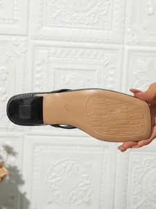 Detailed view of the anti-slip sole and square toe of black high heel thong sandals.