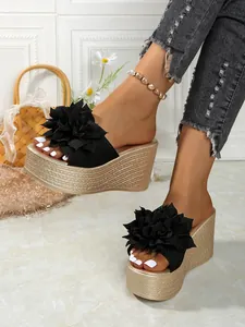 Vue détaillée des sandales compensées à fleurs noires sur un mannequin
