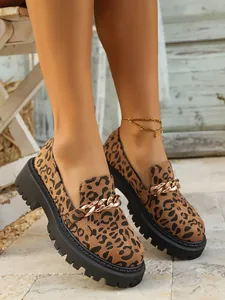 Close-up of leopard print platform loafers with elegant gold chain detail and suede finish.