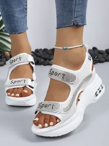 Close-up of white platform sandals with rhinestones and Sport logo velcro straps