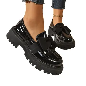 Elegant black patent leather platform loafers featuring a stylish oversized bow detail