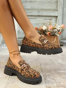 Close-up of leopard print platform loafers with gold chain detail and thick black sole
