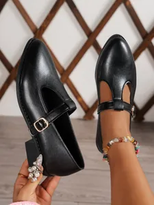 Close-up of elegant black T-strap Mary Jane shoes featuring a gold buckle and block heel