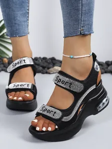 Close-up of black platform wedge sandals featuring rhinestone straps and Sport text.