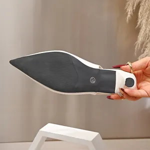 Detailopname van de antislip zwarte zool en hak van een witte sandaal met puntige neus