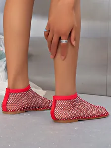 Detailed macro view of red mesh flat sandals with sparkling rhinestone embellishments