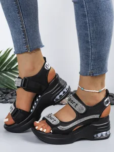 Close-up of black platform sandals with rhinestone Sport lettering and mesh texture