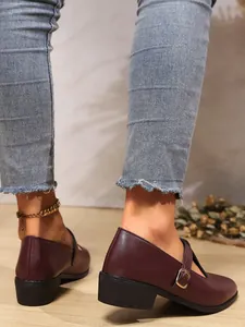 Detail of burgundy Mary Jane loafers with chunky heels and an adjustable buckle strap.