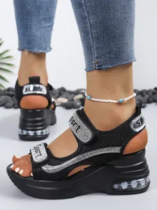 Close-up of black wedge sandals with sparkling rhinestone straps and thick platform sole