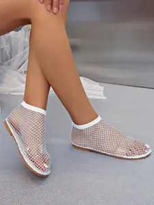 Detail of white fishnet mesh flat sandals with sparkling rhinestone embellishments