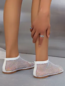 Close-up of white mesh flat sandals with iridescent rhinestones on model's feet