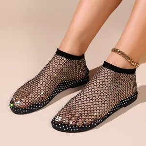 Close-up detail of black fishnet flat sandals adorned with shimmering crystal rhinestones