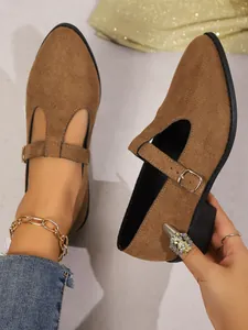 Close-up of brown suede Mary Jane shoes with chunky heels and elegant T-strap detail.