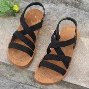 Macro view of black elastic cross straps and perforated footbed of women's flat sandals