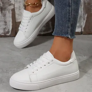 Close-up of white low-top sneakers with lace-up design and textured faux leather finish.