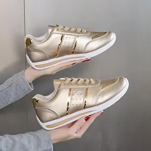 Vista laterale di sneakers metallizzate color oro con lacci e suola in gomma bianca