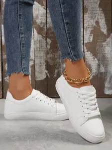 Macro view of stylish white casual sneakers featuring a trendy gold chain anklet accessory