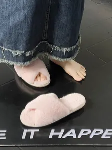 Primo piano di pantofole rosa di peluche con cinturini incrociati su una modella.