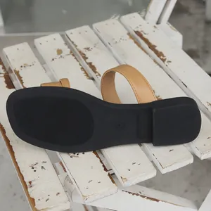 Macro detail of the durable black anti-slip sole on vintage tan leather flat sandals