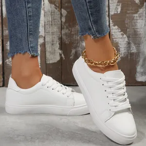 Close-up of stylish white casual low-top sneakers with lace-up design on model feet