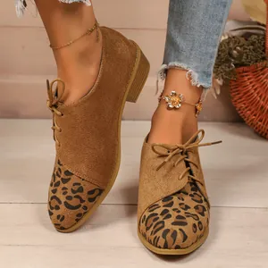 Detail view of brown suede loafers with leopard print toes and side lace-up design