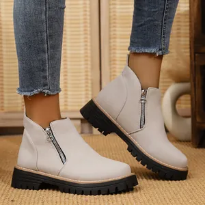Detailed view of beige suede ankle boots with side zipper and chunky lug sole.
