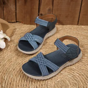 Detail of navy blue women's sandals featuring woven cross straps and a velcro closure.
