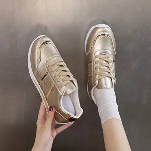 Vista dettagliata delle scarpe da ginnastica metallizzate oro per donna con suola bianca.