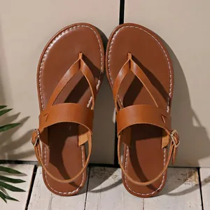 Detailed top view of brown flat thong sandals with gold buckle and white stitching